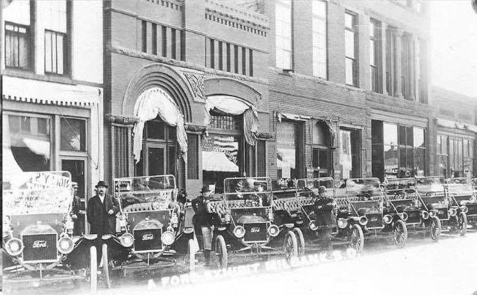 Vintage photo of our building on Main Street, Milbank, with a row of early Ford cars parked out front