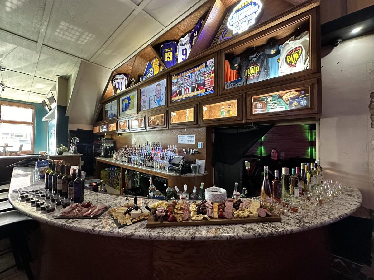 The bar at The Pump 2.0: curved granite bar top, back bar lined with sports jerseys and TVs
