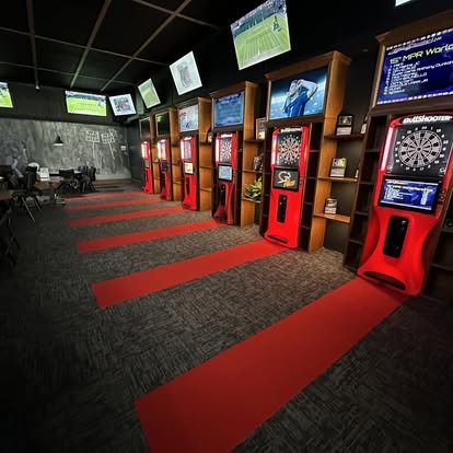 The dart room at The Pump 2.0: a row of red dart machines under TVs